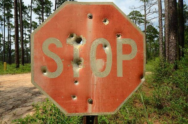 very-old-faded-stop-sign-with-bullet-holes-in-forest.jpg